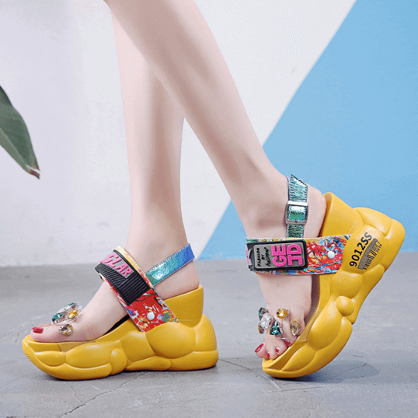 Yellow fashion platform sandals for women with colorful straps and jeweled embellishments on feet
